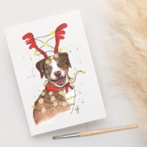 Foto van kerstkaart met aquarel van een hond met kerstgewei